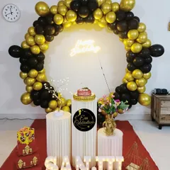 An elegant black and gold birthday theme. The circular balloon arch, neon sign, and white plinths create a very modern and sophisticated look.