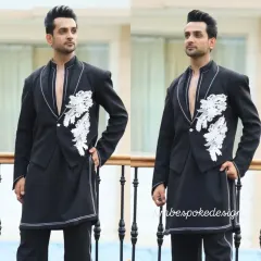 A unique fusion look combining a waistcoat and a tuxedo jacket. This black open-front piece features white floral embroidery and is layered over a long kurta for a stylish, multi-dimensional outfit.