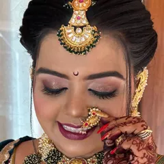A close-up of the bridal makeup, showing the soft shimmer on the eyes and the perfectly blended base. The traditional 'nath' and 'chandrakor' bindi are essential details for an authentic Maharashtrian bride.