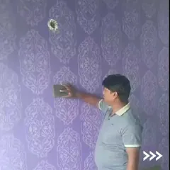 Here, one of our team members is applying a classic damask stencil pattern to a rich purple wall. This technique requires careful alignment and application to ensure a seamless, continuous design across the entire surface.