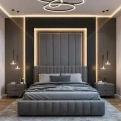 This design features a bold, contemporary aesthetic with a floor-to-ceiling upholstered headboard framed by dramatic backlighting. The monochromatic grey palette and modern lighting fixtures create a sleek and sophisticated look.