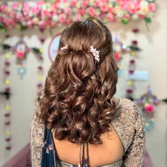 A half-up, half-down hairstyle with soft curls and delicate pearl accessories, perfect for a sangeet or reception.