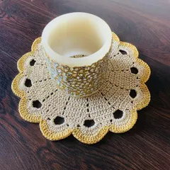 This doily in a natural beige color has a simple yet elegant design with a scalloped, openwork border. It's shown here under a mosaic candle holder.