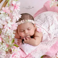 A close-up on a peacefully sleeping baby, framed by delicate pink cherry blossoms. This shot highlights the baby's perfect features and the soft, dreamy atmosphere.
