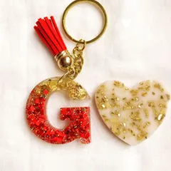 Another popular initial keychain design. The letter 'G' is filled with sparkling red glitter and a touch of gold, making for a vibrant and personal accessory.