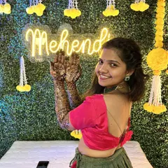 A modern and chic Mehendi setup. We use a lush green artificial wall as the base, adding a custom neon sign for the event and delicate floral hangings to complete the look.