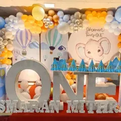 A first birthday party with an elephant and hot air balloon theme, featuring large 'ONE' letters and a custom backdrop.