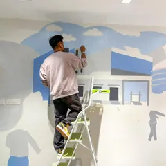 Here I am on a step ladder, blocking in the first layers of color for a new mural. Every piece starts with a blank wall and a vision, and this is the moment it starts to take shape.