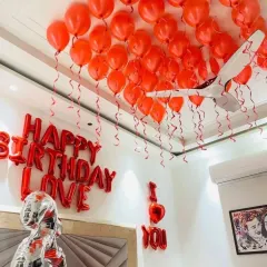 A view of the red balloons covering the ceiling, each with a dangling ribbon, creating a festive canopy over the room.