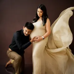 A classic pose filled with love, as the dad-to-be listens to the baby bump. The flowing fabric of the gown adds a touch of elegance to this timeless maternity portrait.