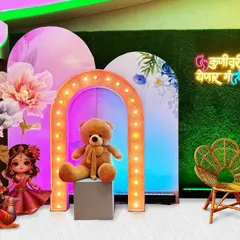 This compact setup shows how a teddy bear theme can be both adorable and budget-friendly. A central teddy bear prop is highlighted by a marquee light arch and flanked by colorful printed backdrops for a fun photo corner.