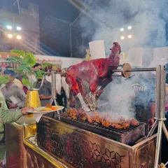 Guests watch as a whole tandoori goat is expertly carved at the live barbecue station, ready to be served.