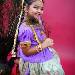 A beautiful portrait of a young girl in traditional South Indian attire, with a "moggina jade" (floral braid) and peacock feathers. Her smile is absolutely radiant.