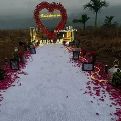 A wide view of our hillside proposal decoration, showing the full path leading to the 'Marry Me' marquee letters and the heart-shaped floral arch. The natural landscape in the background adds to the epic scale of the moment.