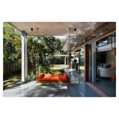 The deep, polished concrete verandah of the House of Canopies, featuring a traditional swing. This transitional space serves as an open-air living room, perfectly embodying the seamless flow between indoor comfort and outdoor serenity.