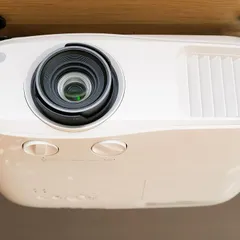 A close-up of a professional-grade 4K projector, ceiling-mounted for a clean and permanent installation. This placement ensures the projector is out of the way and perfectly aligned with the screen.