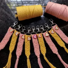 We also make macrame bag charms, perfect for gifting. These pink and yellow ones feature a beautiful woven pattern and a small heart charm for a little extra love.