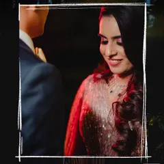 A close-up shot of the bride looking down with a gentle smile, as her partner stands beside her during an evening function.