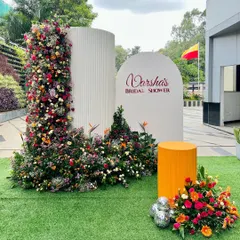 This outdoor bridal shower for Varsha featured a unique setup with a curved, textured backdrop and a stunning floral installation. The bright colors and modern design made for a truly memorable celebration.
