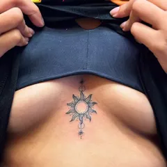 A delicate sun tattoo on the sternum. This is a great example of a small, meaningful piece in a popular placement, done with clean dot work and fine lines.