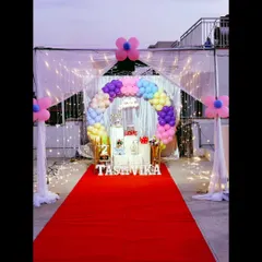 A magical terrace decoration featuring a red carpet entrance and a canopy of sheer curtains with fairy lights. The rainbow balloon arch adds a splash of color.