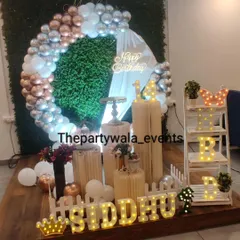 A modern ring decoration with a grass wall backdrop and a mix of rose gold, silver, and white balloons.