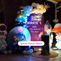 An out-of-this-world space-themed birthday party, complete with a galaxy backdrop, planet cutouts, rocket ship props, and a custom neon sign for the birthday boy.