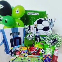 For the ultimate sports fan, I create theme-based hampers that celebrate their passion. This football-themed gift box for a Messi fan includes an Argentina jersey, themed snacks, balloons, and custom cutouts for a winning birthday surprise.