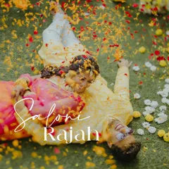 A unique aerial shot of the couple lying on the grass, covered in flower petals, capturing a moment of playful romance during their Haldi.
