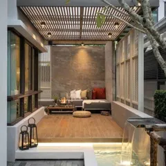 This design creates an intimate outdoor seating area with a slatted wood pergola and a small water feature. The combination of wood decking, stone walls, and the sound of water makes for a truly serene escape.