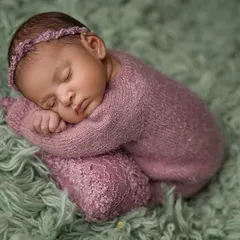 A classic newborn pose, with the baby curled up peacefully. The delicate lace details on the wrap and the matching headband add a touch of elegance to this simple portrait.