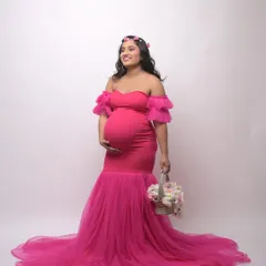 A full-length view of the popular hot pink mermaid gown. Accessorized with a flower crown and basket, this studio photo shows how you can personalize your maternity shoot style.