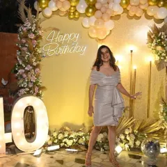 Another shot of the birthday girl enjoying her special night, posing in front of the custom-designed gold and floral backdrop.