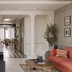 Arched doorways and classic wall paneling create a sophisticated structure in this living area. A pop of color from the coral sofa adds warmth and personality, balanced by neutral tones and natural elements for a timeless yet lively feel.