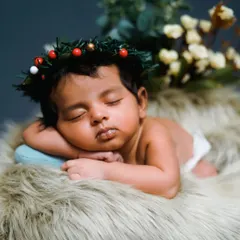 A peaceful sleeping newborn, captured during a Christmas-themed session. I use soft fur blankets and delicate props like this festive wreath to create a cozy and adorable setting for your baby's first photoshoot.