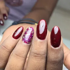 A beautiful wine-red manicure with a sparkling accent nail. The deep red is complemented by a nail filled with purple and silver glitter flakes for a touch of glamour.