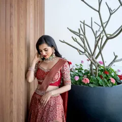 A modern and chic look for a pre-wedding event. The focus is on a bold red lip and clean, defined eyes, paired with a beautiful brocade lehenga.
