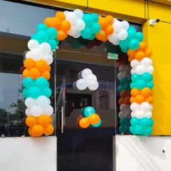 This balloon arch was created for a glass storefront entrance. The orange, white, and teal colors provide a vibrant and welcoming look for customers.