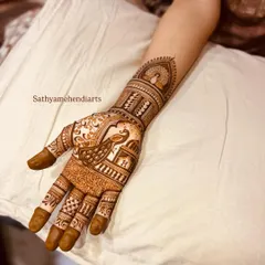 A traditional bridal design with a prominent peacock on the palm. The pattern includes classic elements like checkerboard fillers and floral bands, extending up the forearm.