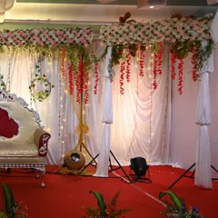 For a softer, more romantic feel, I used hanging floral arrangements in pink and red against a white draped background. The overhead floral panels and warm lighting add depth and elegance to the stage.