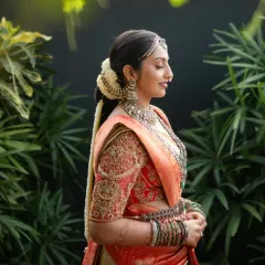 This bride is the picture of elegance in a red and cream bridal saree. The blouse is heavily embroidered with traditional motifs, while the sheer net back adds a subtle, modern detail.
