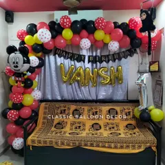 Even for home parties, we can create a fun Mickey Mouse theme. This setup includes a balloon arch and character balloon over a sofa for a first birthday.