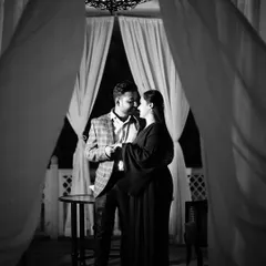 A timeless black and white portrait framed by soft curtains. This intimate shot uses shadows and light to create a classic, romantic mood perfect for a pre-wedding album.