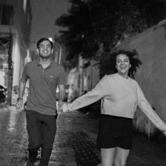A black and white shot of a couple running hand-in-hand down a wet city street, full of joy and spontaneity.