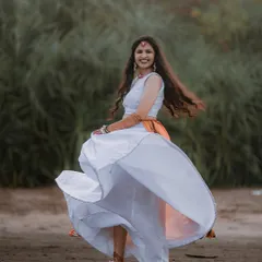 A beautiful twirling shot of the bride during her beachside Haldi ceremony, her white and orange lehenga creating a stunning visual against the natural backdrop.