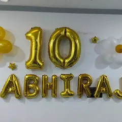 A simple and personalized decoration for a 10th birthday. I used gold foil balloons for the name "ABHIRAJ" and the number "10", along with flower-shaped balloon clusters for a fun touch.