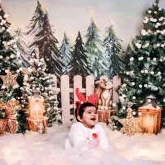 A baby enjoying our snowy forest Christmas theme, complete with reindeer antlers and a happy laugh.