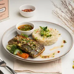 For a lighter yet equally flavorful option, I offer this perfectly seared fish steak. It's served with a zesty chimichurri sauce, herbed rice, and grilled vegetables, creating a balanced and delicious meal.