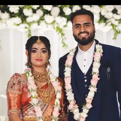 A close-up of a couple at their engagement, with a clean white floral backdrop that makes their traditional outfits stand out.