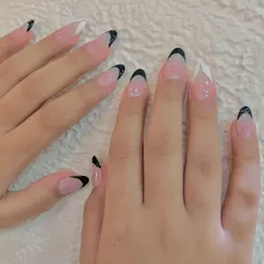 A chic twist on a classic. This look features sharp, almond-shaped nails with a mix of black and white French tips for a modern, high-contrast manicure.